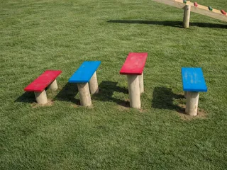 Quatro mesinhas de parada em madeira tratada com tampos coloridos, em circuito de agility