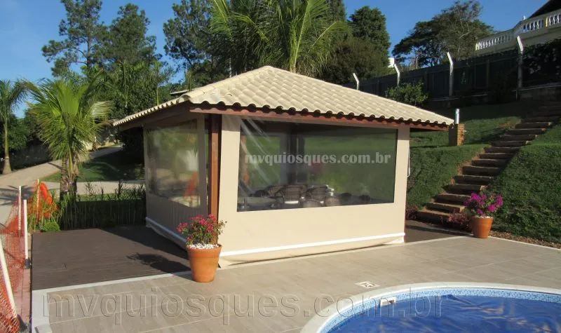 Quiosque com cobertura de telha cerâmica à beira da piscina, com toldos laterais
