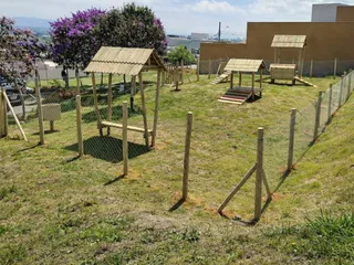 Circuito de agility para cães cercado em área gramada, com passarelas, rampas e abrigos de madeira tratada